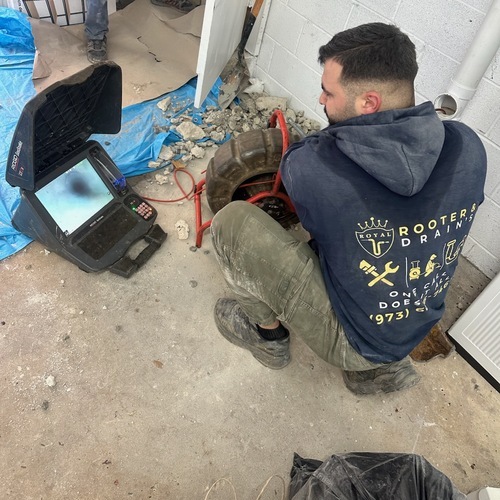 Plumber uses video camera to examine drain.