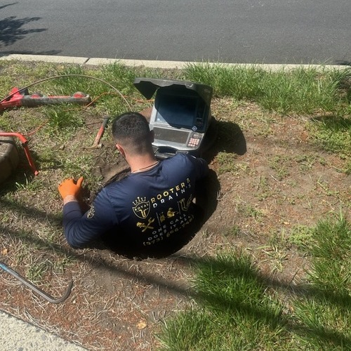 Plumber works on outdoor drain.